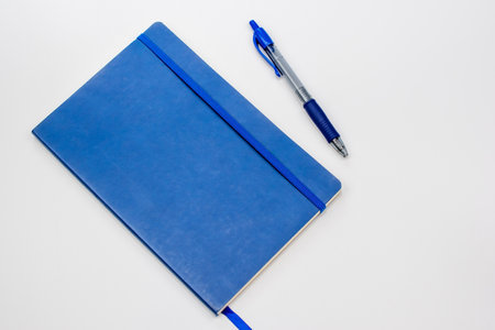 Blue notebook and pen on a white background. View from above.の写真素材