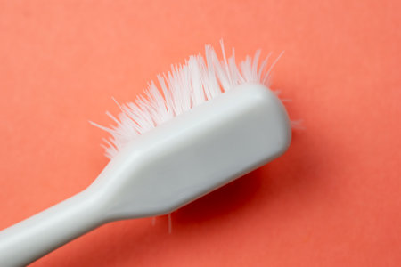 Toothbrush with white bristles on a red background close upの写真素材