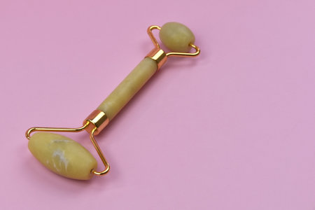Jade face roller on a pink background. Face massage tool.の写真素材