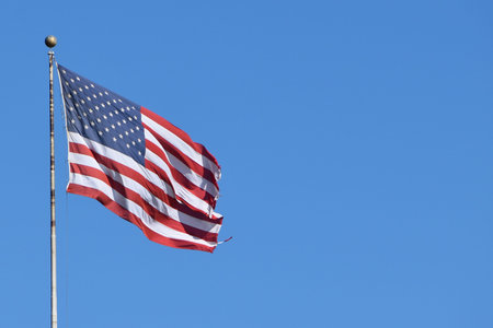 American flag waving in the wind against a blue sky with copy space
