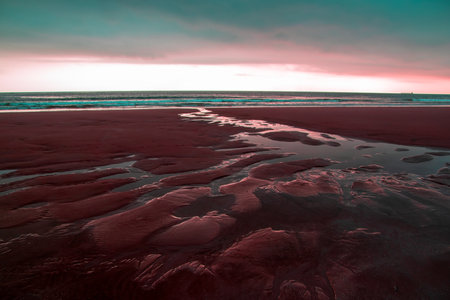 Beautiful sunset at the beach with pink sand and red water.の写真素材