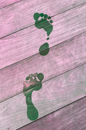 Green footprint on pink wooden background. Footprints in the form of a human footの写真素材