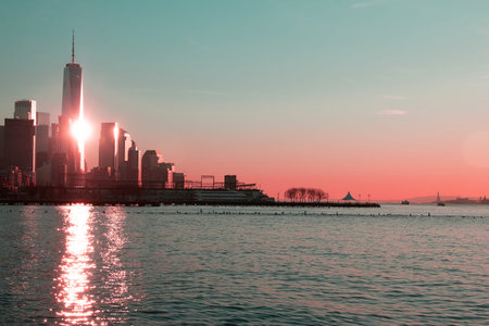The sun is reflected in the skyscrapers of Manhattan, sunset in cityscape, sun sky over the sea,...