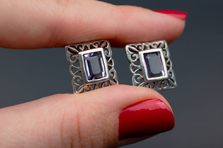 Jewelry earrings in a woman's hand on a gray background
