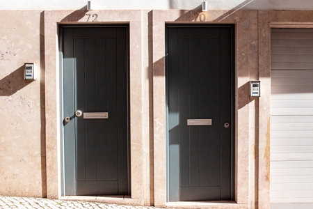 Two closed wooden doors in a row on the facade of a buildingの写真素材