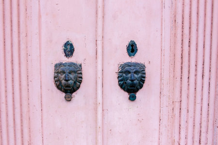 Ancient door knocker on a pink wooden door in the old cityの写真素材