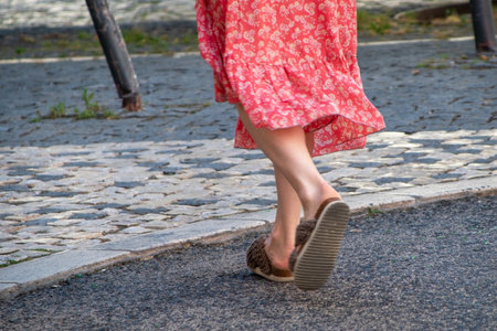 Close up of woman legs walking on cobblestone street in summerの写真素材