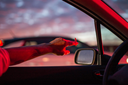 Hand of a man in a red sweater driving a car at nightのeditorial素材