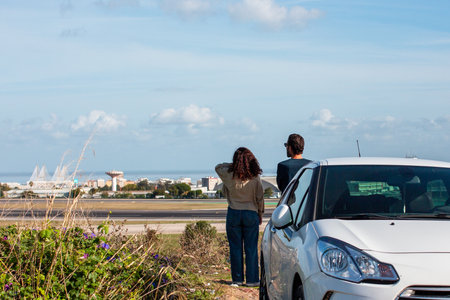 Young couple standing in front of the car and looking at the seaのeditorial素材