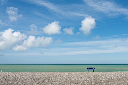Bench facing the sea, on a pebble beachの写真素材