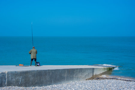 Fisherman on a pontoon facing the seaの写真素材