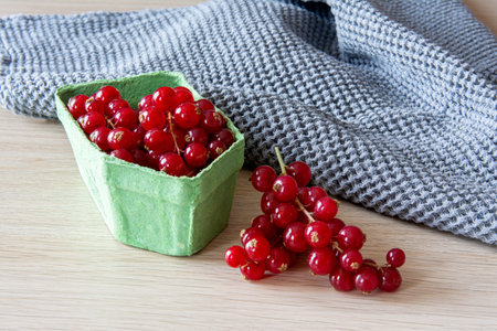 Red currants in a cardboard basket and bunches on a tableの写真素材