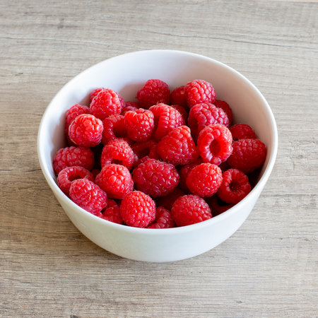 Raspberries in a white bowl. Square photo format.の写真素材