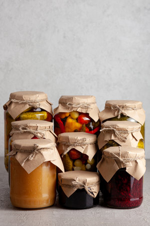 Assortment of homemade canned goods including fruit preserves, pickled cucumbers, peppers, and assorted vegetables. Traditional food preservation and organic storage concept.の写真素材