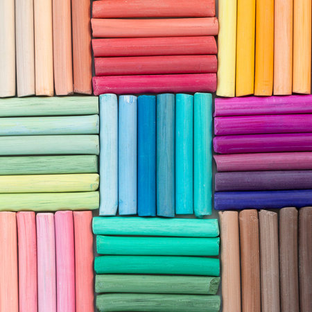 Rainbow pastel crayons in rows as background. Square image