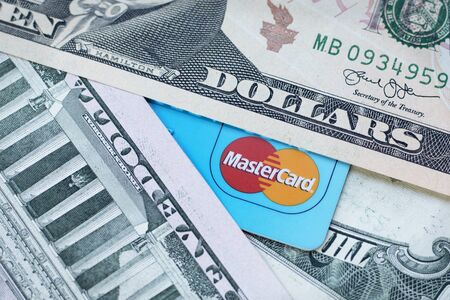 Credit card with Mastercard logo and US dollar banknotes closeup. Moscow, Russia - May 2019. Image, business, finance, banking, travelのeditorial素材