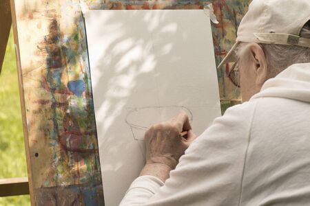 Senior grey-haired man draws with left hand at art studio for elderly people. Moscow - June 1, 2019のeditorial素材