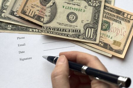 A person signing a document, agreement, contract. Dollar background. A page with text: Phone, Email,  Date, Signatureの写真素材