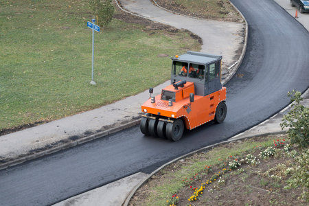 Roller compactor during operation. Road renewal process, compacting asphalt. Road construction,...