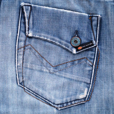 Moscow, Russia - 17 November 2020: Back pocket of blue retro jeans with flap, button, orange stitching as background. Vintage style distressed jeans. Squareのeditorial素材