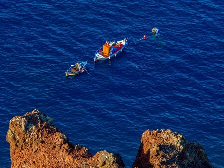 Fisherman catching a fish in the morning, above view from cliff. Santorini, Cyclades, Greeceの写真素材