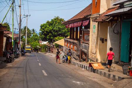 BALI, INDONESIA - December 01, 2019: Traditional Balinese Tribe Village. Cars and motorbikes drive along the street in Bali, Indonesiaのeditorial素材