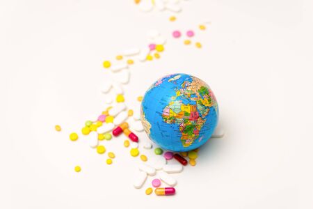 Metaphor of the global pandemic of the corona virus. The globe and pills on white background. Selective focus. Health and medicine concept. Top viewの写真素材