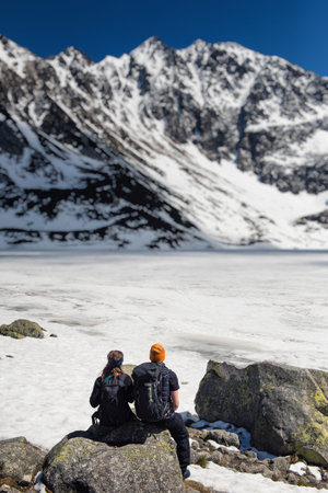 photo of a snowy mountain peak, man is sitting with his back to the camera and makes selfie
