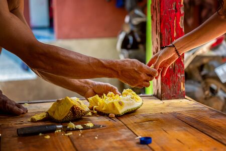 photo of hands of local balinese man cut exotic fruit durian in his house and share with tourist. Bali, Indonesiaの写真素材