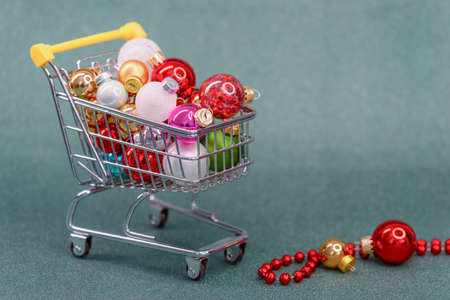 christmas concept, shopping cart full of colorful xmas baubles on blurred green color background with copy spaceの写真素材