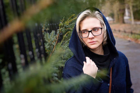 Outdoor lifestyle portrait of pretty young hipster woman in a cold autumnal park.の写真素材