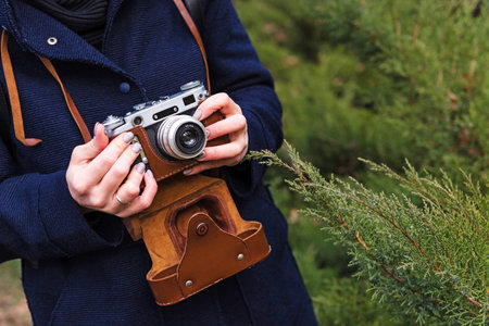 Close up of young woman hipster holding retro film camera in hands. Woman's hands holding an old...