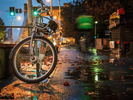a bicycle left on night rainy city streetの写真素材