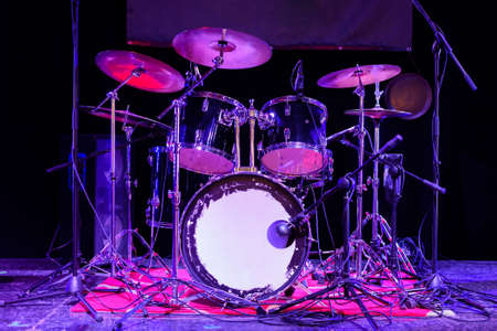 The drum set on the stage. The drum kit is in a dark space and is illuminated by neon light.の写真素材