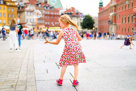 little girl playing with soap bubbles in a city centerの写真素材