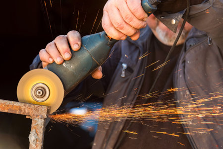 Man working with grinder saw, close up view on tool. Electric saw and hands of worker with sparks....