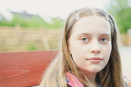 Portrait of cute blonde hair teenage girl looking at camera, close up with blurred background