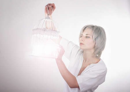 young blond woman catches a light to a bird cageの写真素材