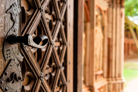 Old open wooden door with carved pattern and metal knob in a medieval castleの写真素材