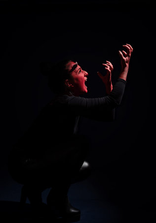 Screaming woman with long black hair and with face paint for halloween, demon woman with red face...