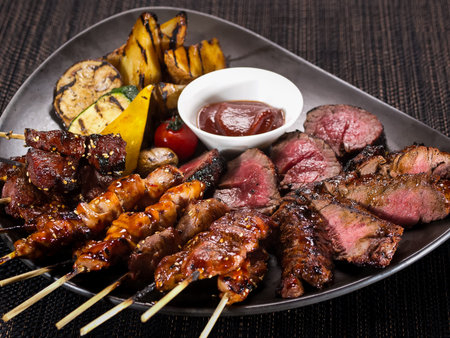 meat plate, set of different grilled skewers and grilled sliced filet mignon on a plate served with...