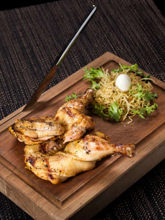 grilled chicken on a wooden serving board with knife, served with fresh lettuce, vertical photoの写真素材
