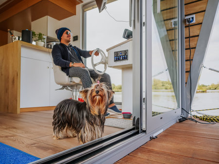 Young person wearing pajama and knitting hat clothing and with his yorkshire terrier dog steering...