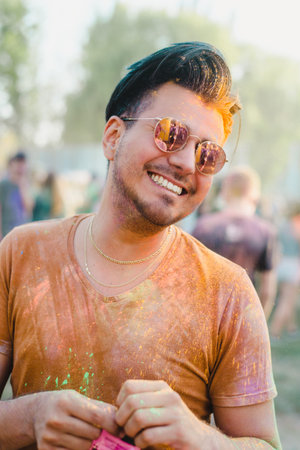 handsome smiling black hair man with colorful face having fun on holi color festival