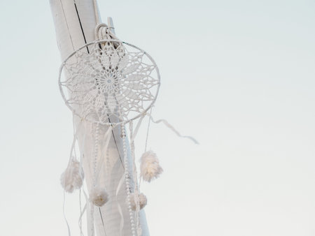 white handmade dreamcatcher hanging on light blue background