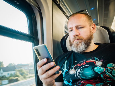 mature bearded man in train with smartphoneの写真素材