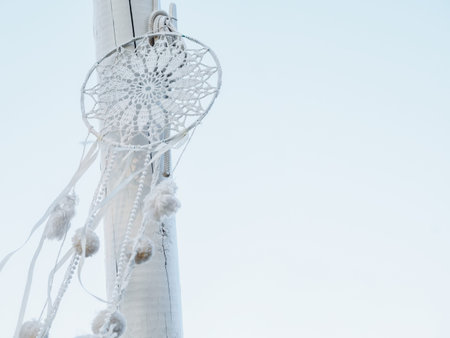 white handmade dreamcatcher hanging on light blue background