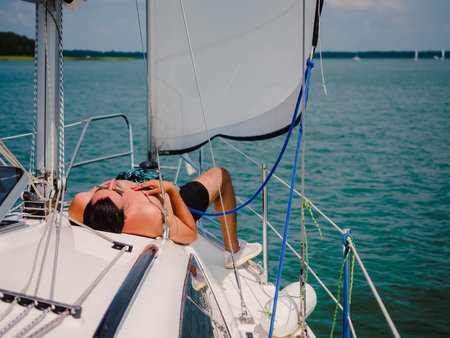 young person sunbathing on a sailboat under the sail