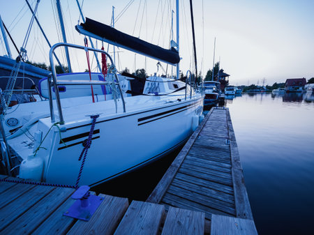 sailboat moored on wooden jetty in the port at the evening time
