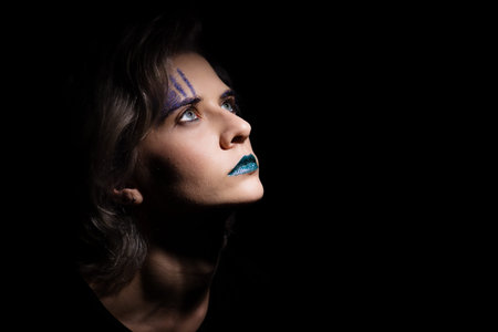 dark dramatic female portrait with trendy teal color makeup. blond hair woman looking up, mysterious...